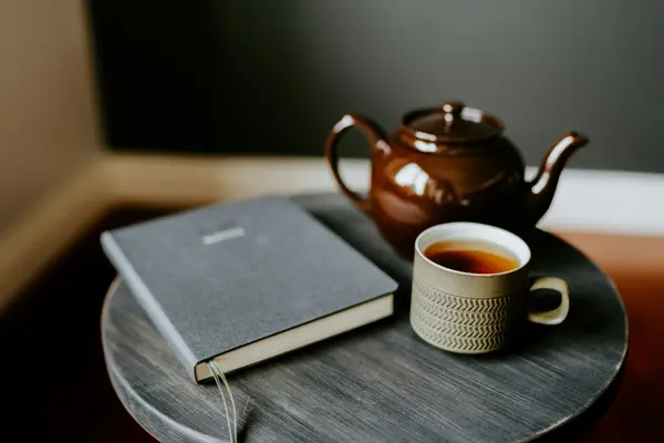Taza de té y un cuaderno sobre una mesa de madera