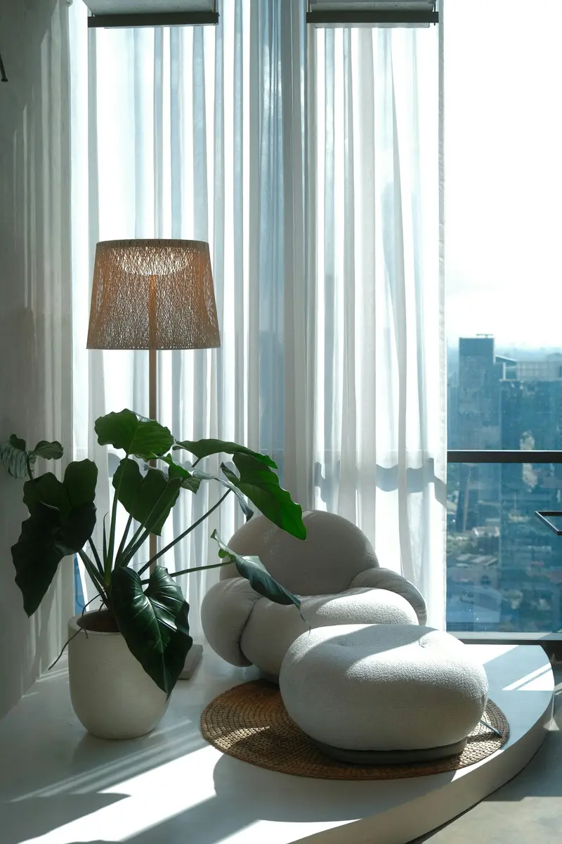 Rincón del consultorio con una lámpara, una planta grande y un sillón junto a la ventana